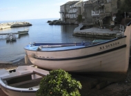 A pedestrian area in the village of Erbalunga, with restaurants and cafes, and boats tied up in front of the houses.